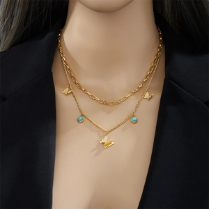 Double-layered gold butterfly necklace with turquoise beads on model in black blazer