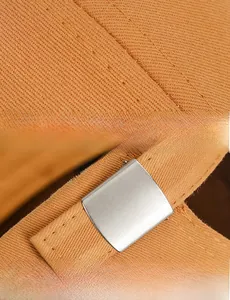 Close-up of double stitching and adjustable silver metal buckle on cotton baseball cap