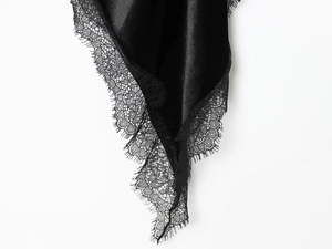 Detailaufnahme von schwarzem Satinstoff mit exquisitem Wimpernspitzen-Besatz am Rand
