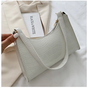 Close-up of white faux leather underarm bag featuring a glossy crocodile embossed texture