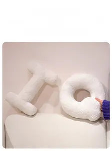 Close-up of soft beige alphabet pillows in I and Q shapes with plush sherpa texture