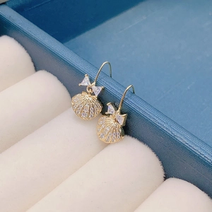 Elegant gold bow earrings with shell design and shimmering cubic zirconia in a jewelry box