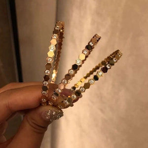 Detail of three-piece golden honeycomb bangles with sparkling pavé-set diamonds