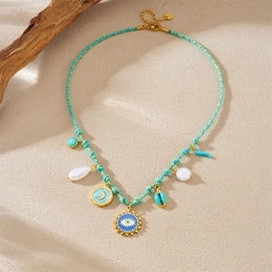 Blue woven cord necklace with evil eye, moon, and shell pendants on sandy background