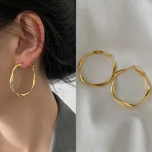 Detail view of 4cm twisted gold hoop earrings showing size scale and model try-on