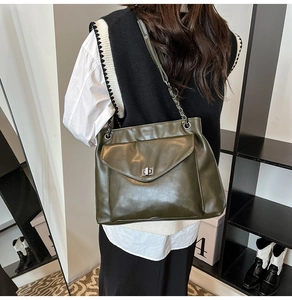 Dettaglio borsa tote verde oliva scuro con chiusura girevole argento e tracolla a catena