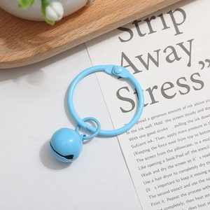 Detail of light blue painted metal ring with matching bell charm on white background