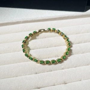 Detail of emerald oval gemstone bracelet on velvet display with gold-plated setting