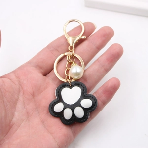 Chic black and white leather cat paw keychain with gold hardware and a pearl accent