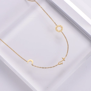 Elegant gold necklace with crescent moon, heart and Greek key circle on transparent block