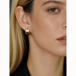 Elegant wide golden S925 sterling silver hoop earrings worn by a model in a close-up view