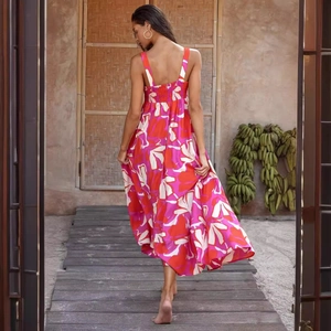 Tropical floral print backless maxi dress with red and pink patterns on a resort boardwalk