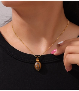 Detail of tiger eye stone pendant on a gold titanium steel chain worn by a model