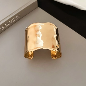 Macro detail of high-shine gold cuff bracelet with artistic hammered texture surface