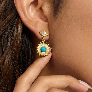 Evil eye and turquoise sun drop earrings in gold stainless steel shown on ear