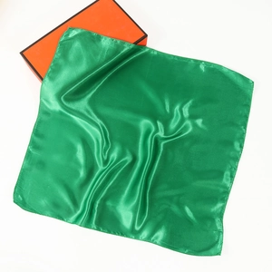 Detailed view of emerald green satin square scarf with smooth silk finish and orange gift box