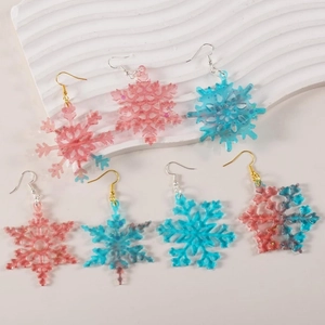 Macro detail of snowflake resin pendants with glitter and gradient colors on a tray
