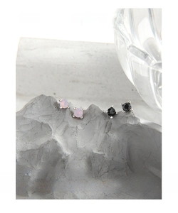 Macro shot of 925 sterling silver four-prong stud earrings with pink opal and black stone