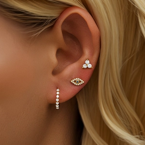 Macro shot of 925 silver gold-plated evil eye and diamond stud earring set on ear