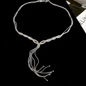 Layered silver fringe necklace with woven cross design and delicate beads on black background