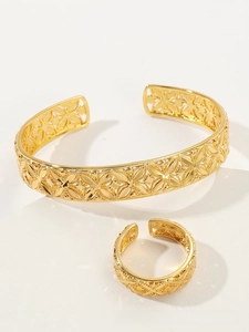 Detail of gold-plated hollow geometric flower pattern on cuff bracelet and ring set