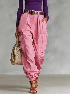 Detail of pink cargo pants with multi-pocket design and retro brown leather belt