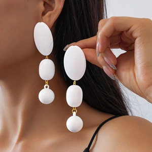 Détail de boucles d'oreilles géométriques blanches en acrylique portées par un mannequin