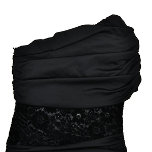 Detail of black dress featuring ruched fabric texture and delicate lace pattern accents