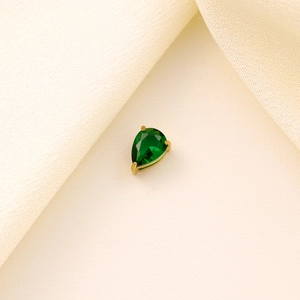 Close-up of a pear-shaped green zircon pendant set in a golden claw setting base