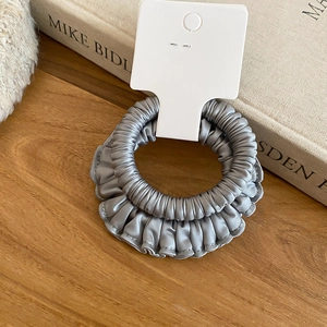 Gros plan d'un chouchou en satin gris plissé sur une table en bois pour accessoires cheveux