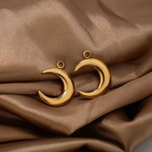 Detailed view of large gold stainless steel crescent moon pendants on silk fabric
