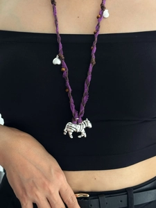 Détail d'un collier ethnique en cordon de coton violet avec perles en bois et pendentif zèbre