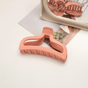 Close-up of a large matte peach hair claw clip with a sleek minimalist design