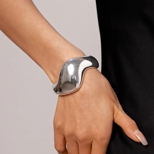 Poliertes silbernes unregelmäßiges Manschettenarmband am Handgelenk vor schwarzem Hintergrund