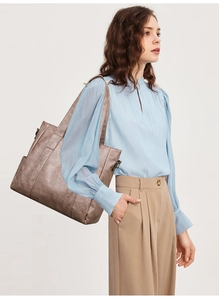 Detailed view of bronze tote bag set worn by model with high capacity features