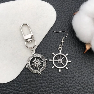Detailed macro view of silver nautical compass keychain and ship wheel anchor earrings