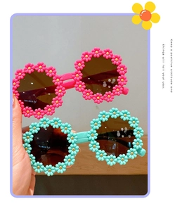 Detail of pink and blue daisy-shaped sunglasses with dark round lenses for toddlers
