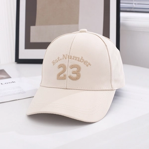 Detail of embroidered Est. Number 23 on a beige canvas baseball cap on a white table