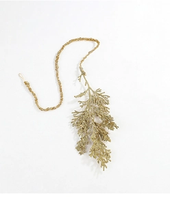 Detail of glittery gold cypress leaf pendant for Christmas tree decoration with hanging cord