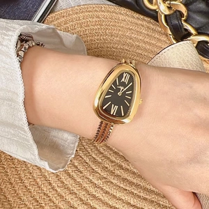 Detail of snake head watch with black dial and triple gold chain strap on wrist