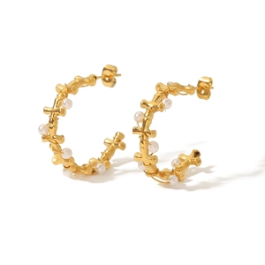 Golden C-shaped earrings with cross design and pearl accents on white background