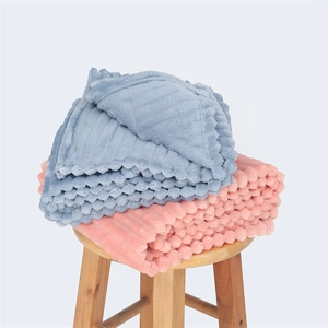 Morandi blue and pink striped flannel blankets folded on a wooden stool
