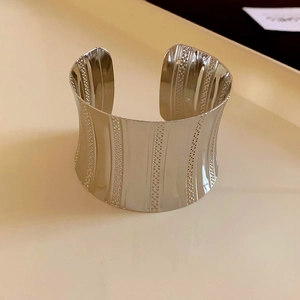 Detail of silver drop open cuff bracelet showing polished surface and vertical dot patterns