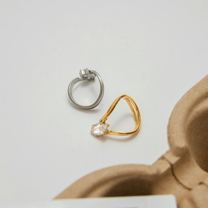Detail of minimalist wavy 18k gold and silver rings set with oval cubic zirconia stones