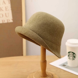 Cappello cloche in lana verde kaki con bordo arrotolato su un supporto di legno