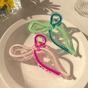 Detail of jelly-colored bow shark hair clips in green and pink on a decorative plate
