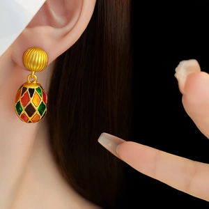 Detail of vintage palace style enamel oval earrings worn by model on black backdrop
