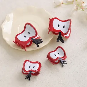 Cute red apple-shaped hair claws for summer styling set on a ceramic plate
