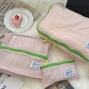 Three-piece pink travel organizer set with green zippers on white plush carpet