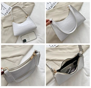 Detail views of white crocodile pattern underarm bag featuring gold zipper and interior space
